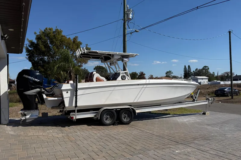 Slide: The Image of 2005 Renegade 29CC boat on trailer with Mercury engine, parked on paved driveway. - 2