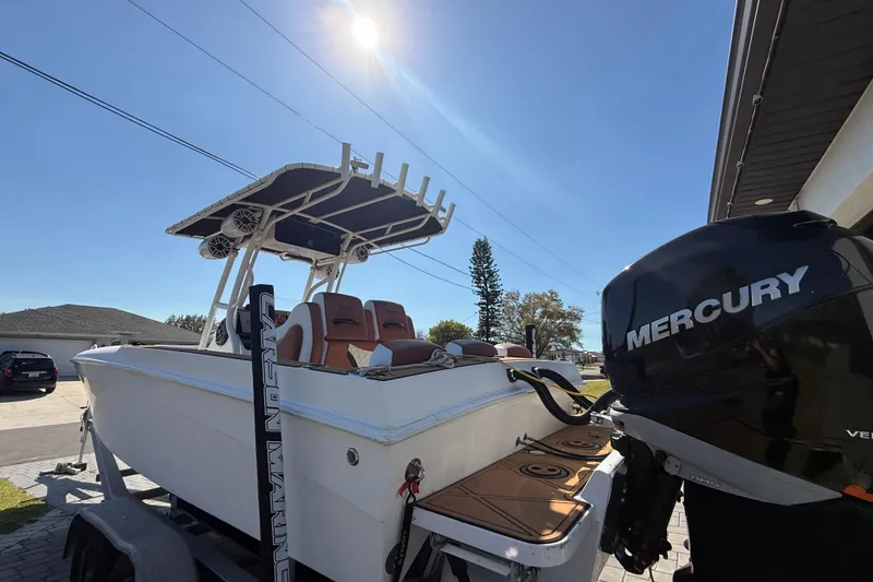 Slide: The Image of 2005 Renegade 29CC boat with Mercury engine, parked outdoors under clear blue sky. - 3