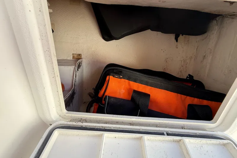 Slide: The Image of Storage compartment of a 2005 Renegade 29CC boat with an orange and black bag inside. - 32