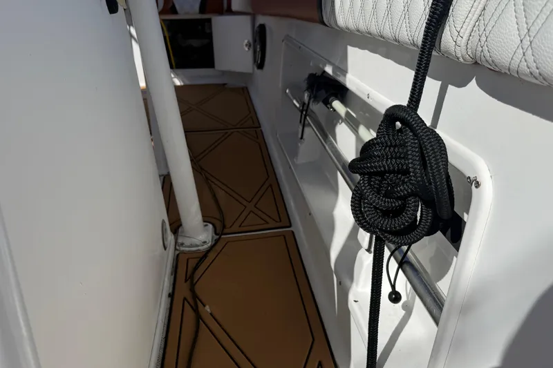 Slide: The Image of Interior view of a 2005 Renegade 29CC boat, featuring a coiled black rope and tan flooring. - 38