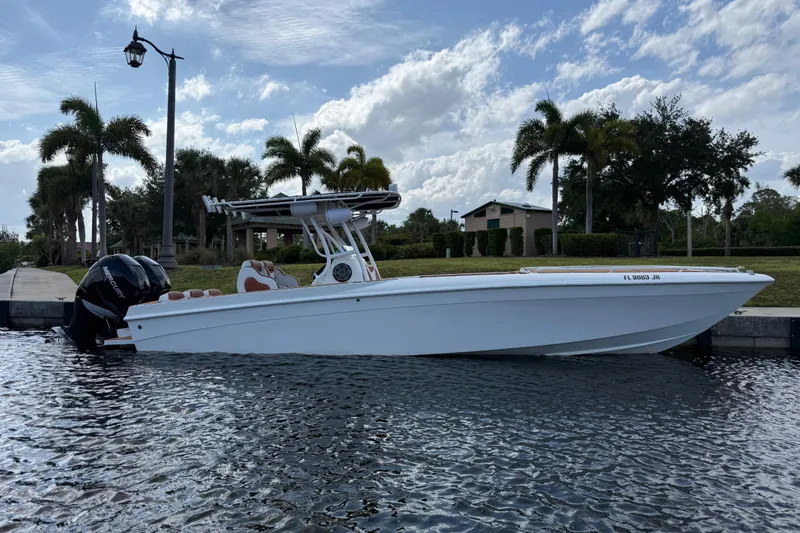 Slide: The Image of 2005 Renegade 29CC boat docked on a sunny day with palm trees in the background. - 64