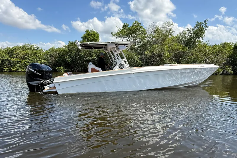 Slide: The Image of 2005 Renegade 29CC boat on calm water, surrounded by lush greenery and blue sky. - 70