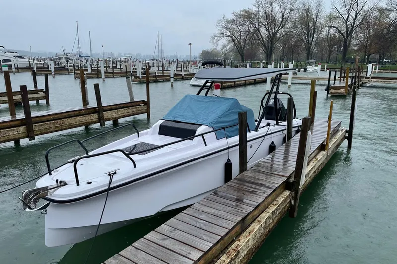 Slide: The Image of 2023 Axopar 25 Cross Top boat docked in a marina on a cloudy day. - 1