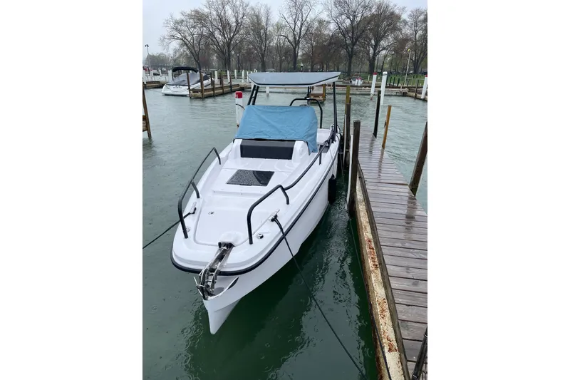 Slide: The Image of 2023 Axopar 25 Cross Top boat docked in a marina, featuring a sleek design. - 2
