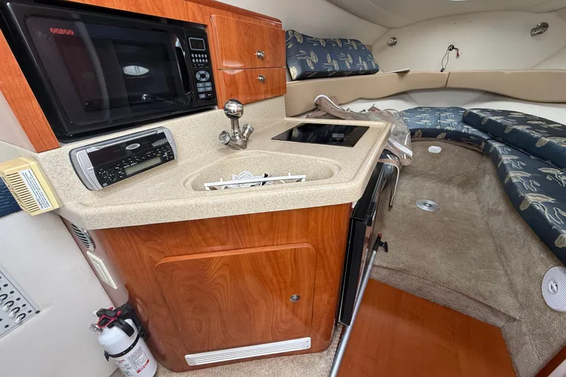 Slide: The Image of 2004 Larson 274 boat interior with kitchenette, microwave, and seating area. - 12