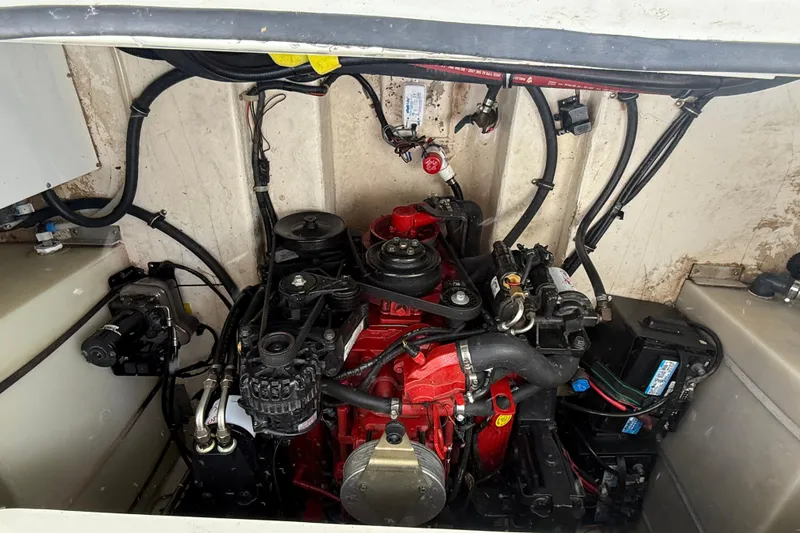 Slide: The Image of Engine compartment of a 2004 Larson 274 boat, featuring a red engine and wiring. - 14