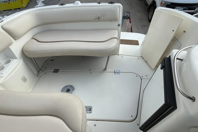 Slide: The Image of 2004 Larson 274 boat interior with beige seating and storage compartments. - 15