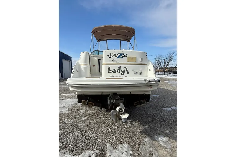Slide: The Image of 2004 Larson 274 boat with canopy, parked on gravel, rear view. - 21