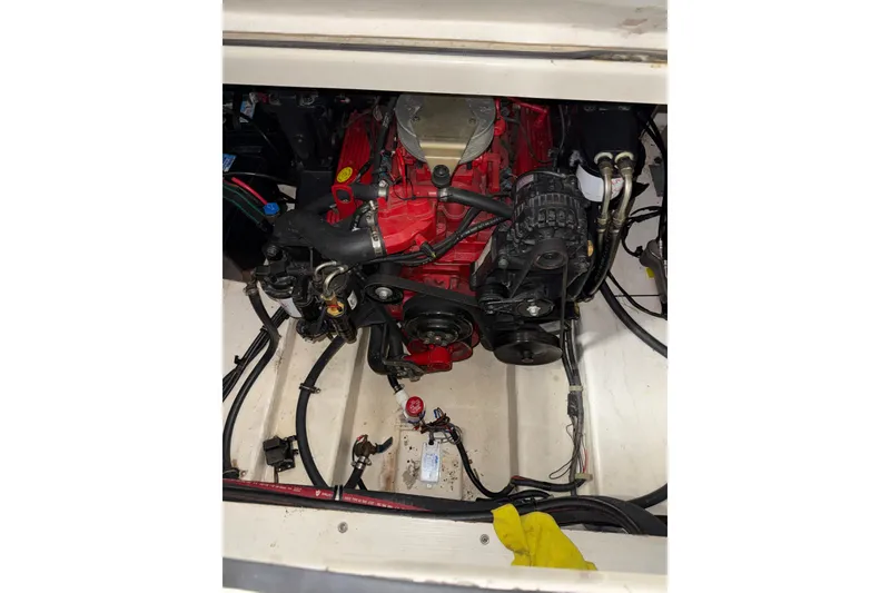 Slide: The Image of Engine compartment of a 2004 Larson 274 boat, featuring a red engine and various components. - 23