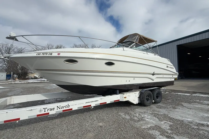 Slide: The Image of 2004 Larson 274 boat on trailer outside a warehouse, ready for transport. - 7