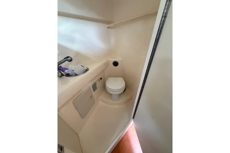 Slide: The Image of 2004 Larson 274 boat bathroom with compact toilet and sink. - 8