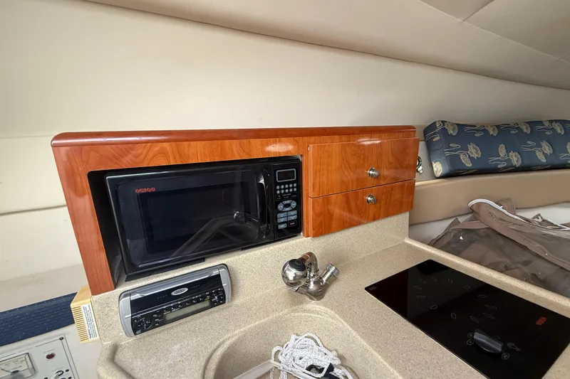 Slide: The Image of 2004 Larson 274 boat interior with microwave, stove, and wooden cabinetry. - 9