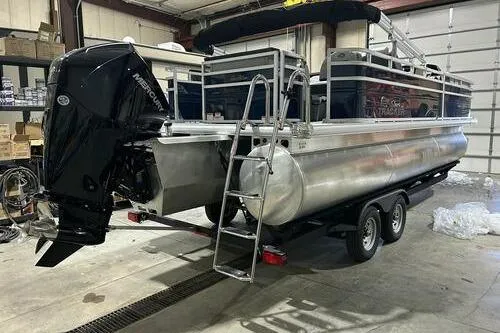 Slide: The Image of 2026 Sun Tracker SportFish 22 XP3 pontoon boat in a garage, featuring a Mercury outboard motor. - 3