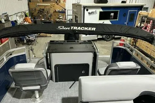 Slide: The Image of 2026 Sun Tracker SportFish 22 XP3 pontoon boat interior with seating and canopy in a garage. - 6
