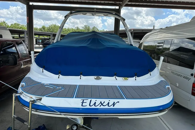 Slide: The Image of 2013 Rinker 276 Captiva Bowrider with blue cover, parked in a sheltered area. - 1