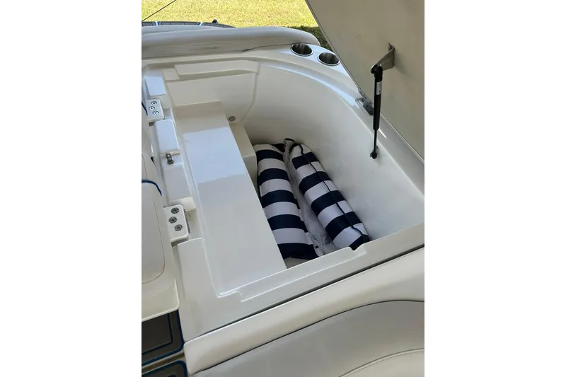 Slide: The Image of 2013 Rinker 276 Captiva Bowrider storage compartment with striped cushions. - 14