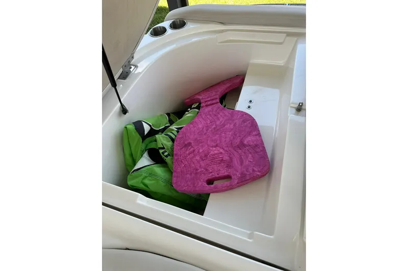Slide: The Image of Storage compartment in 2013 Rinker 276 Captiva Bowrider with pink and green accessories. - 15