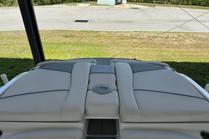 Slide: The Image of 2013 Rinker 276 Captiva Bowrider boat with cushioned seating, parked on grass. - 16