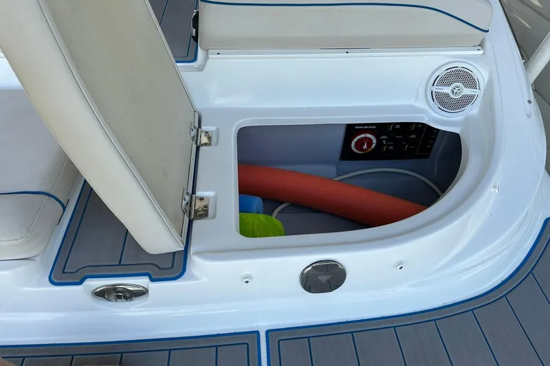 Slide: The Image of 2013 Rinker 276 Captiva Bowrider storage compartment with seat, speaker, and pool noodle. - 17