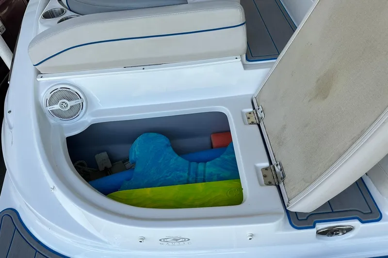Slide: The Image of 2013 Rinker 276 Captiva Bowrider storage compartment with colorful pool noodles and speaker. - 19