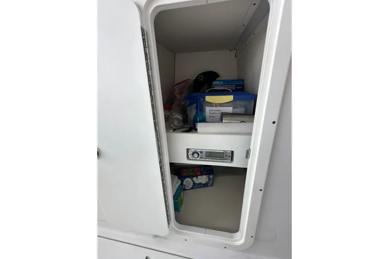 Slide: The Image of Storage compartment in a 2013 Rinker 276 Captiva Bowrider, containing various items and a stereo system. - 28