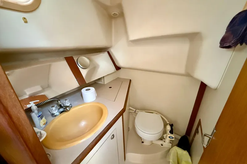 Slide: The Image of Compact bathroom in a 2000 Hunter 290 sailboat, featuring a sink and marine toilet. - 9