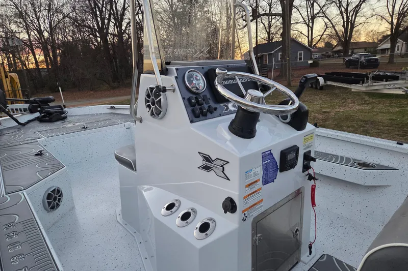 Slide: The Image of 2023 Xpress H22B Bay boat interior with steering console and gauges at sunset. - 18