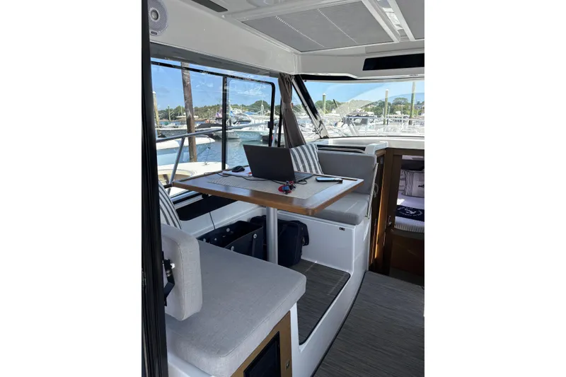 Slide: The Image of Interior of 2020 Jeanneau NC 895 boat with table, laptop, and marina view. - 9