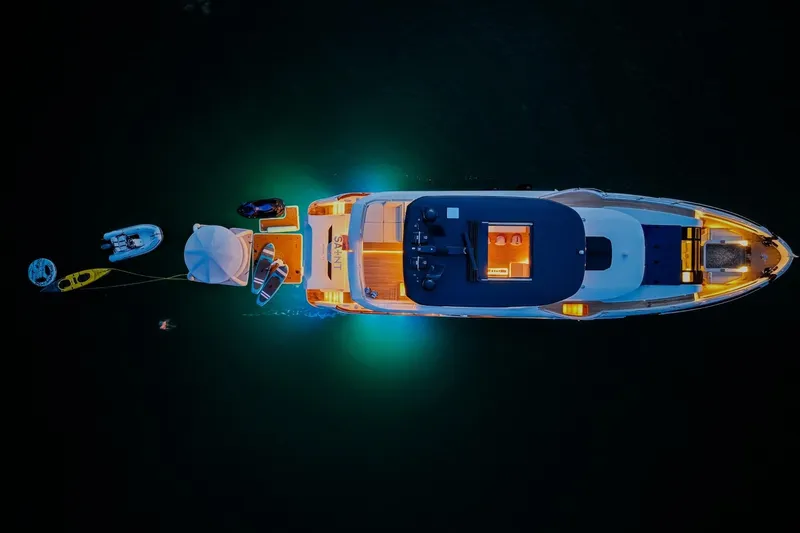 Slide: The Image of Aerial view of illuminated 2021 Sirena 88 yacht at night with watercraft nearby. - 2
