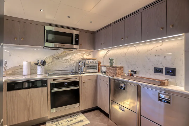 Slide: The Image of Luxurious yacht kitchen with modern appliances, marble backsplash, and elegant cabinetry in a 2021 Sirena 88. - 39