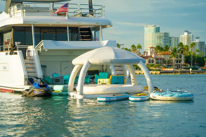 Slide: The Image of Luxury Sirena 88 yacht with inflatable lounge and jet ski on calm water, cityscape background. - 73