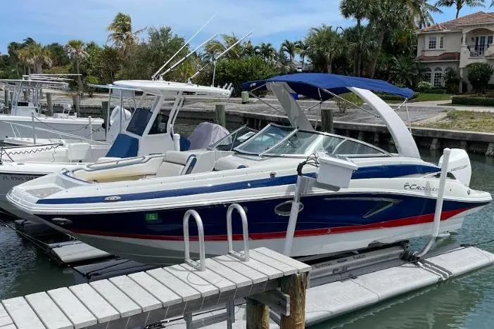 Slide: The Image of 2021 Crownline Eclipse E255 XS boat docked in a marina with palm trees in the background. - 0