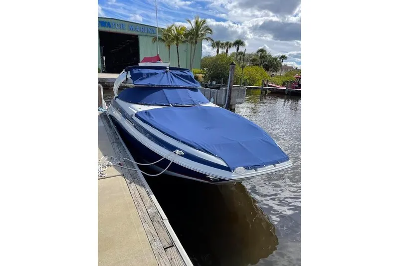 Slide: The Image of 2021 Crownline Eclipse E255 XS boat docked with blue cover, marina background. - 2