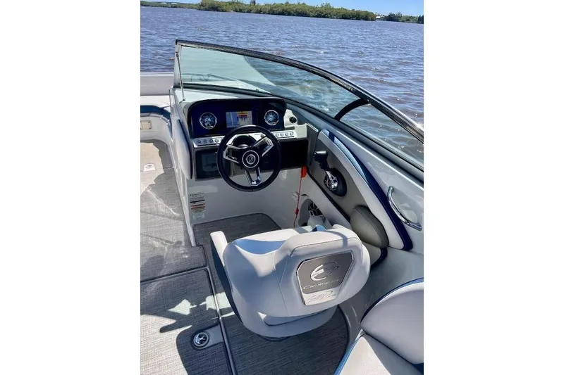 Slide: The Image of 2021 Crownline Eclipse E255 XS boat interior with steering wheel and dashboard on water. - 8