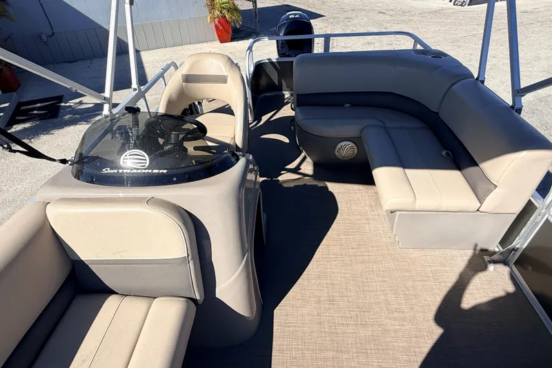 Slide: The Image of 2023 Sun Tracker Party Barge 18 DLX interior with beige seating and helm. - 12