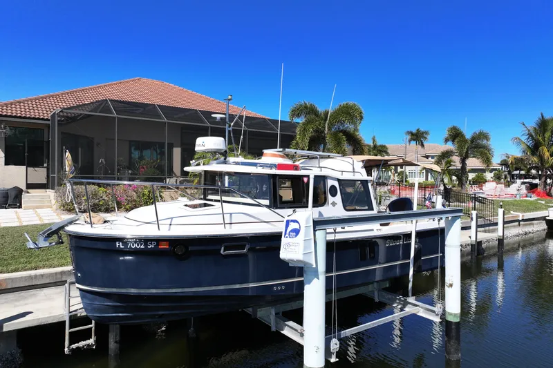 Slide: The Image of 2020 Ranger Tugs R-25 boat docked by waterfront home with palm trees. - 0