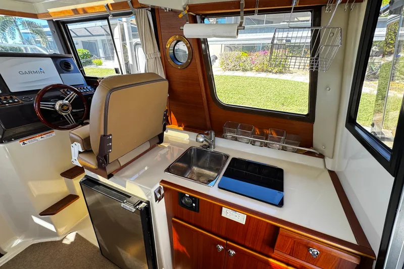 Slide: The Image of 2020 Ranger Tugs R-25 interior with helm, kitchen sink, and storage. - 11