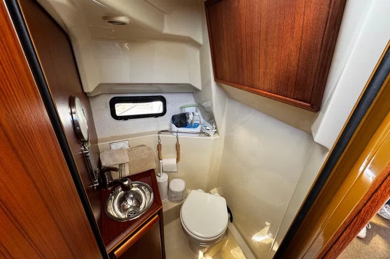 Slide: The Image of 2020 Ranger Tugs R-25 boat bathroom with sink, toilet, and wooden cabinetry. - 16