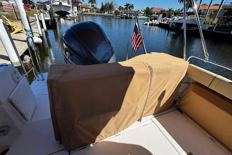 Slide: The Image of 2020 Ranger Tugs R-25 boat docked, covered seating, American flag, sunny marina view. - 17