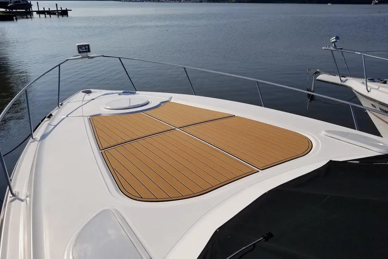 Slide: The Image of 2003 Cruisers Yachts 3470 Express boat deck with wooden panels on calm water. - 15