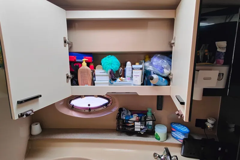 Slide: The Image of Open bathroom cabinet on 2003 Cruisers Yachts 3470 Express, displaying toiletries and personal care items. - 23