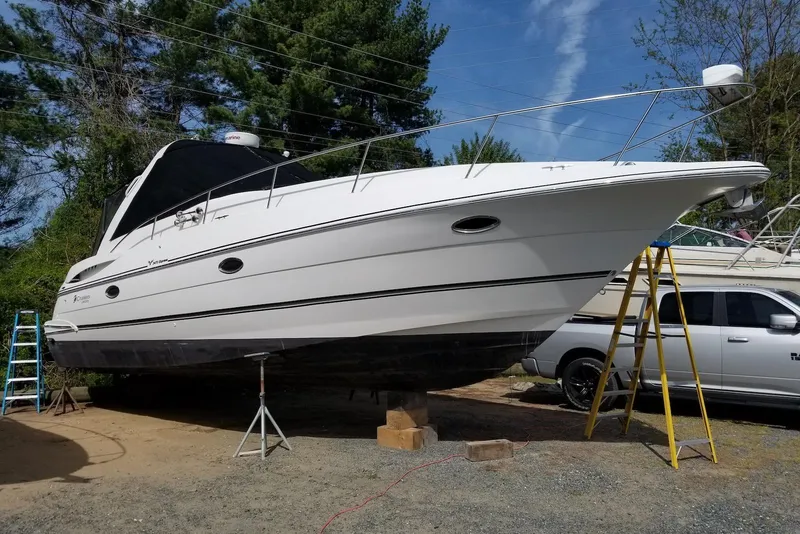 Slide: The Image of 2003 Cruisers Yachts 3470 Express on dry dock, surrounded by trees and vehicles. - 4