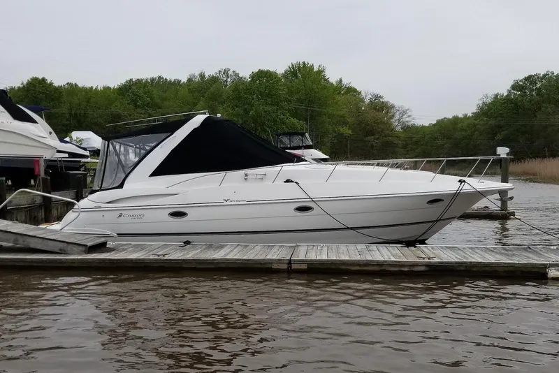Slide: The Image of 2003 Cruisers Yachts 3470 Express docked on a calm river, surrounded by greenery. - 1