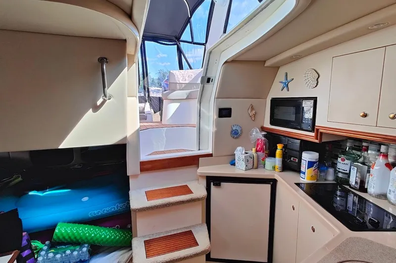 Slide: The Image of 2003 Cruisers Yachts 3470 Express interior with kitchenette, stairs, and nautical decor. - 11