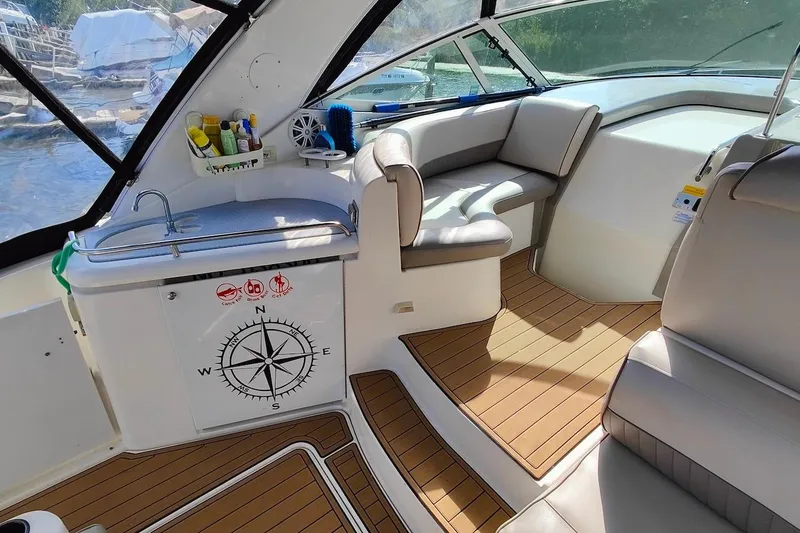 Slide: The Image of 2003 Cruisers Yachts 3470 Express interior with seating, sink, and compass design. - 6