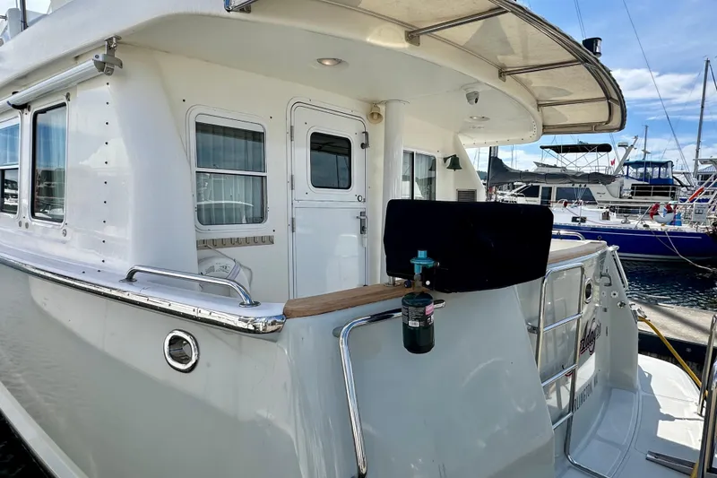 Slide: The Image of 2003 Nordhavn 47 yacht docked at marina, showcasing exterior details and nearby boats. - 5