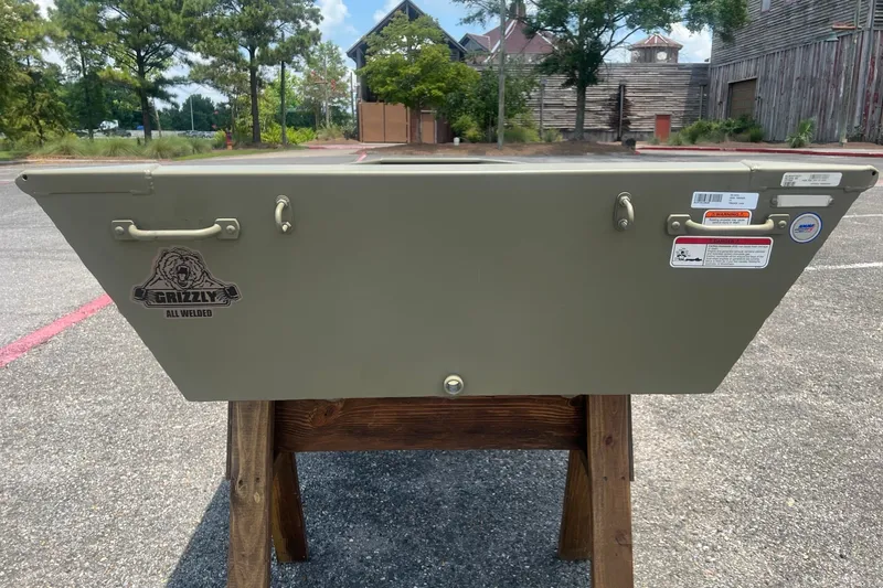Slide: The Image of 2026 Tracker Grizzly 14 Jon boat displayed outdoors on a wooden stand. - 3