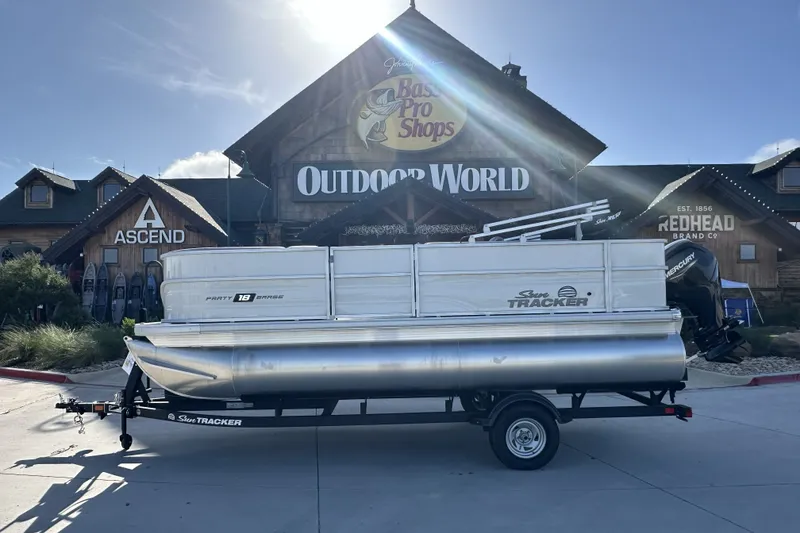 The Image of 2026 Sun Tracker Party Barge 16 DLX pontoon boat outside Bass Pro Shops. - 16