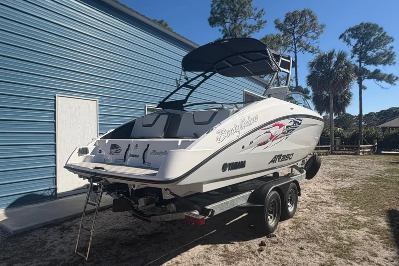 Slide: The Image of 2025 Yamaha Boats AR250 interior with seating, docked near a blue building. - 13