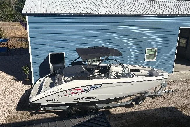 Slide: The Image of 2025 Yamaha Boats AR250 interior with modern seating and steering, outdoor setting. - 14